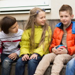 Children communicate sitting on bench in yard